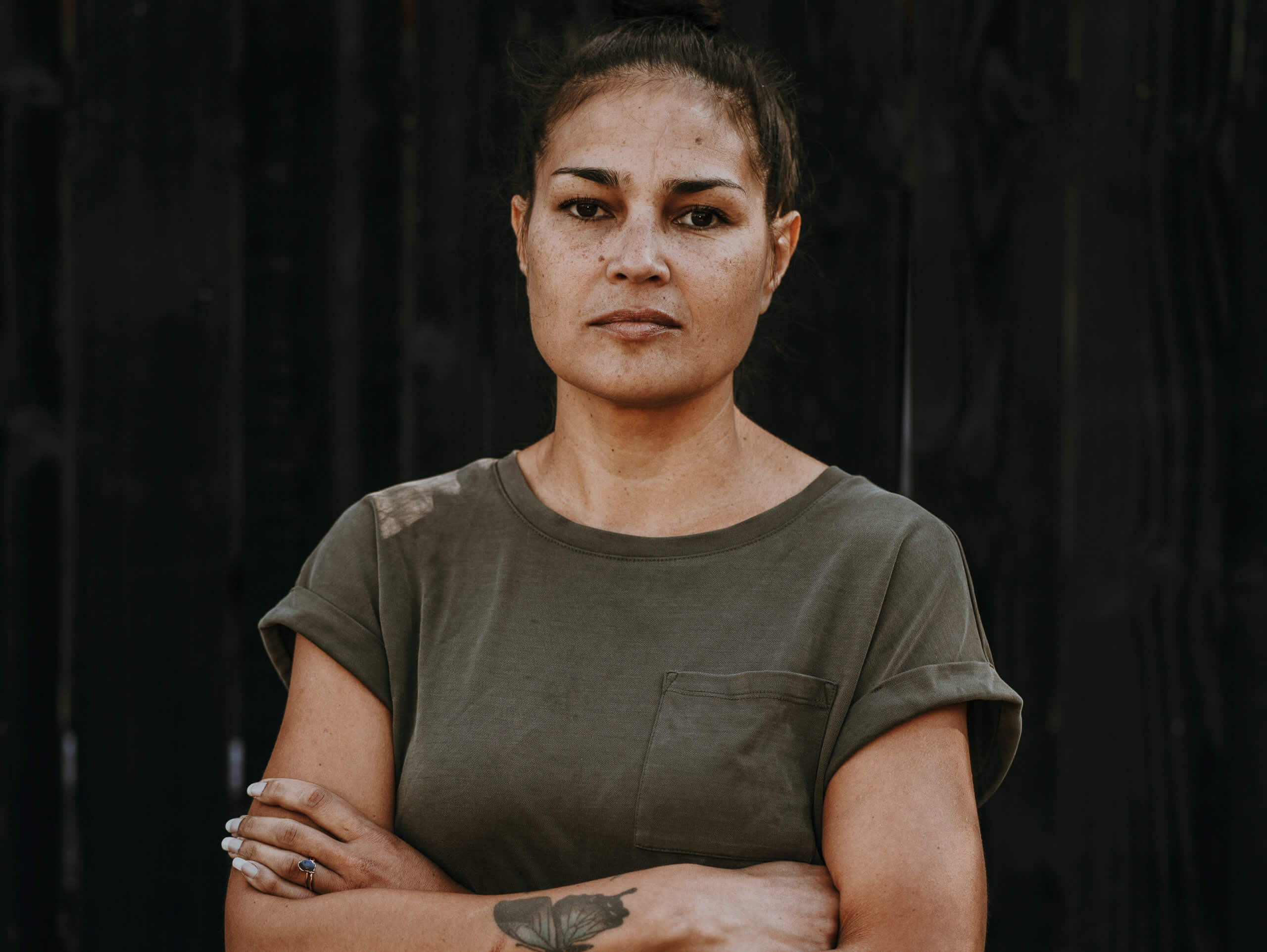 Rohani Foulkes of FOLK Detroit stands arms crossed in from of a black background