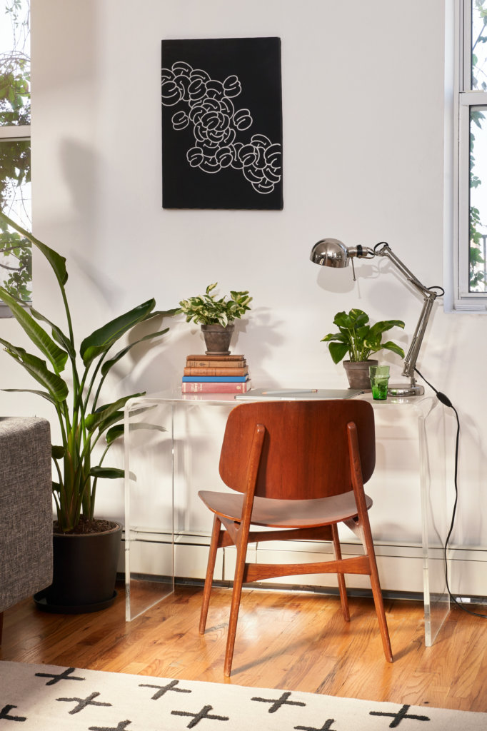 Bird of Paradise next to desk and chair in living room with air conditioning vent